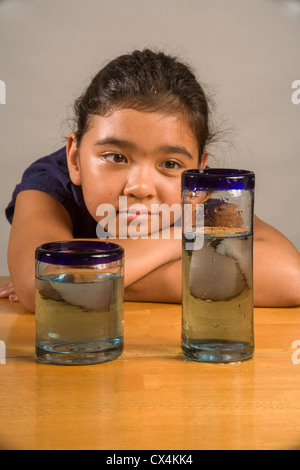 Ein Kind sieht bei identischen Gläser gefüllt mit der gleichen Menge Flüssigkeit Piagets flüssige Erhaltung Experiment nachweisen. Stockfoto