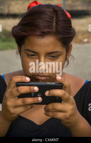 Eine aufgeregt hispanischen Mädchen liest eine Mobbing Nachricht auf ihr Smartphone. Stockfoto