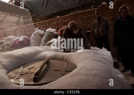 Ein uigurische Mann packt Baumwolle, bevor es in Turpan, Xinjiang, China gesponnen wird Stockfoto