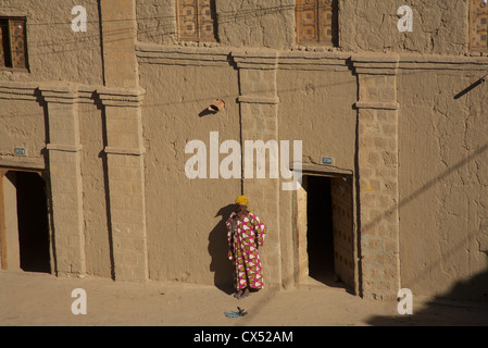 Eine Frau, die außerhalb eines typischen Haus in einer Straße in Timbuktu, Mali, Westafrika Stockfoto