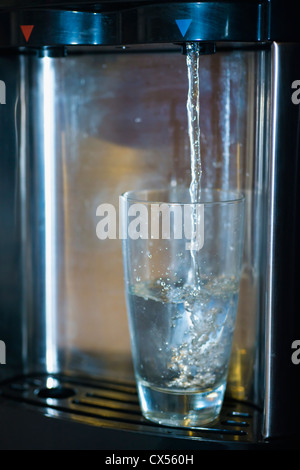 Trinkwasser-Spender füllt ein Glas Stockfoto