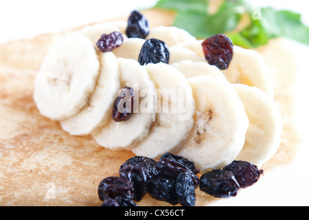 Gerollte dünne Pfannkuchen mit Banane und Rosinen Stockfoto