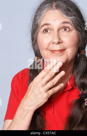 Ältere Frau mit Lächeln und rücksichtsvoll Blick auf ihrem Gesicht. Stockfoto