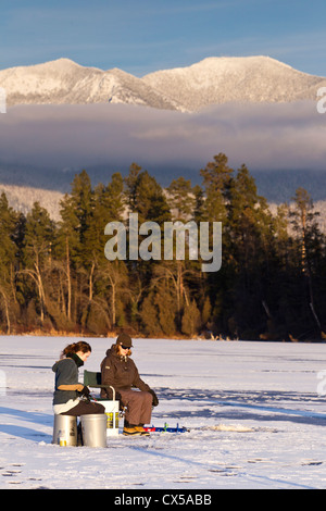 Eisangeln Sie auf McWenneger Slough mit Schwan-Bergen im Hintergrund in der Nähe von Kalispell, Montana, USA. (MR) Stockfoto