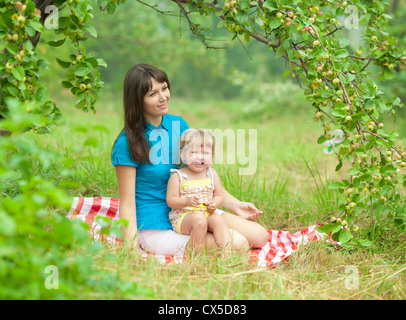 Mutter und Tochter haben Picknick im Freien unter Apple-Ast Stockfoto