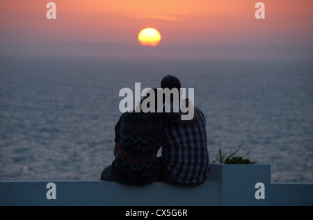 ALGARVE, PORTUGAL. Ein paar beobachten den Sonnenuntergang über dem Atlantik von Praia Carvoeiro. 2012. Stockfoto