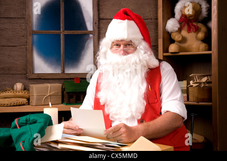 Weihnachtsmann sitzt in seiner Werkstatt einen Brief lesend. Horizontale Komposition. Stockfoto