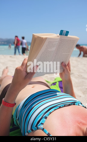 ein Frauen Urlaub Buch am Strand lesen und Sonnenbaden Stockfoto