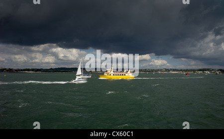 eine Gewitterwolke schwarzer Regen Wetter Ansätze über Poole, während das Meer Boote in Sonnenlicht getaucht sind Stockfoto