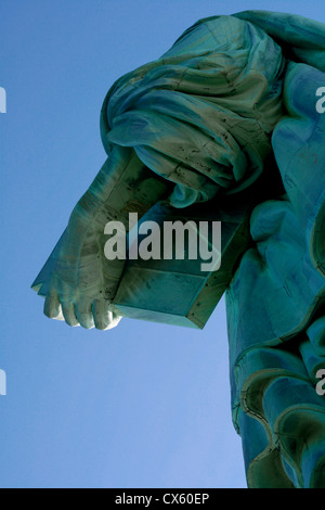 Abstrakte Schuss von der Freiheitsstatue gegen einen tiefblauen Himmel, mit Schwerpunkt auf der Hand, hält ein Buch Stockfoto