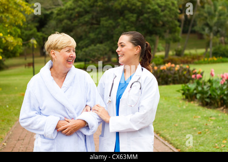fürsorgliche Krankenschwester unter älteren Patienten im Freien spazieren Stockfoto