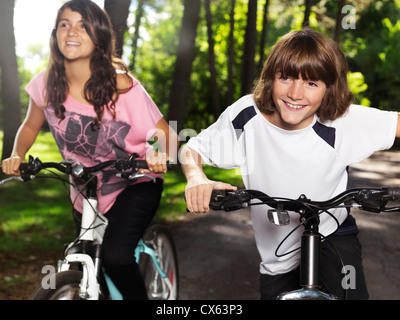 Zwei glückliche lächelnde Kinder Fahrrad in einem Park, Bruder und Schwester, 10 und 13. Aktiven outdoor-Lifestyle. Stockfoto