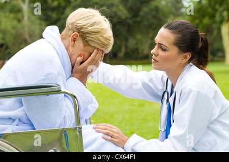 fürsorgliche junge Ärztin trösten einen einsamen Behinderte senior Patienten im freien Stockfoto