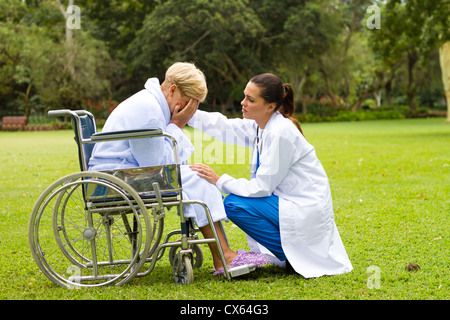 fürsorgliche junge Ärztin trösten einen einsamen Behinderte senior Patienten im freien Stockfoto