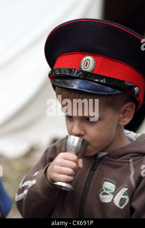 Junge in uniform Mütze von Don Kosaken aus metallischen Becher trinken Stockfoto