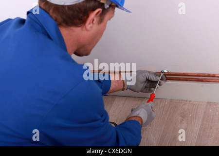 Klempner sichern Rohr zur Wand Stockfoto