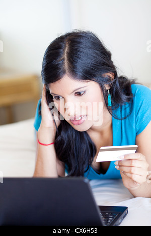 junge Frau Überprüfung Kreditkartensaldo und sieht besorgt Stockfoto