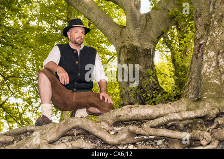 Knienden Mann in bayerischer Tracht im Wald Stockfoto