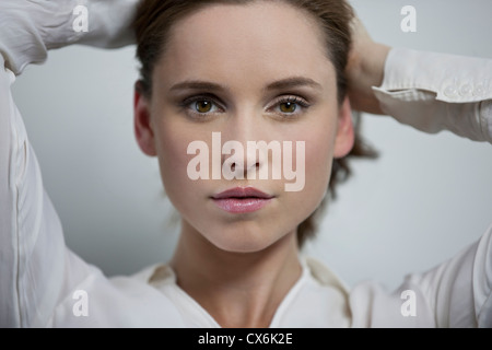 Eine junge Frau hält ihr Haar wieder aus ihrem Gesicht Stockfoto