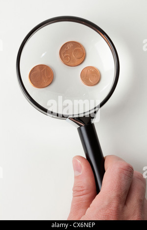 Ein Mann Lupe drei Euro Kupfermünzen, close-up von hand Stockfoto