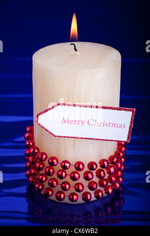 Beleuchteten Weihnachtskerze mit Tag über glänzenden dunkelblauen Hintergrund. Stockfoto