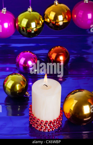 Weihnachtskerze und Kugeln auf glänzenden blauen Hintergrund. Stockfoto