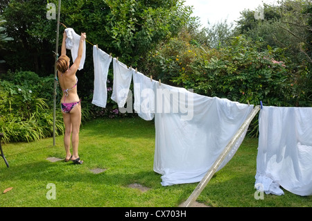 Eine Frau in ihrem Bikini hängt die Wäsche an einem sonnigen Tag in Cornwall, Großbritannien Stockfoto