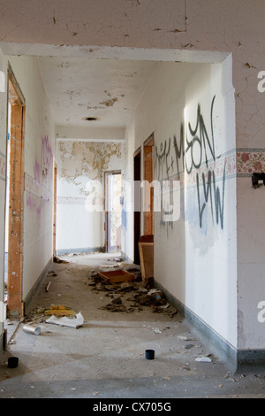 Gang eines verlassenen Gebäudes in Detroit Michigan mit Graffitis an den Wänden und weggeworfene Gegenstände auf dem Boden. Stockfoto