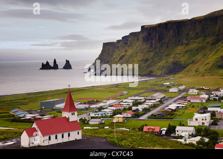 Luftaufnahme über Vik (Vik ich Myrdal) mit seiner Kirche und den Reynisdrangar (Basalt-Meer-Stacks) in der Morgendämmerung, Südisland Stockfoto