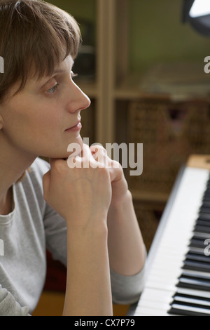 Eine Frau, stützte sich auf ein Klavier, nachdenklich Stockfoto