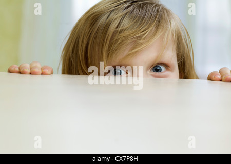 Ein schelmischen Mädchen spähte über den oberen Teil einer Tabelle Stockfoto