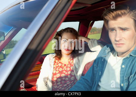 Eine hübsche Rockabilly-Mädchen auf der Suche bei ihrem Freund in Irritation beim Sitzen im Oldtimer Stockfoto