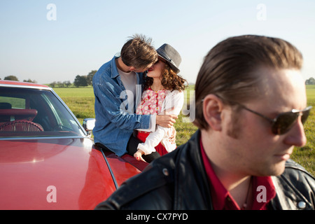 Ein Rockabilly-paar küssen während stützte sich auf einen Oldtimer, der Mensch im Vordergrund Stockfoto