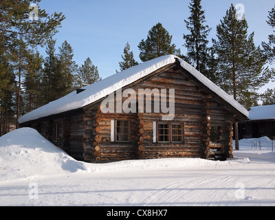 Romantische schneebedeckte Blockhaus zwischen den Bäumen in einer Ferienanlage in Lappland, Finnland. Stockfoto