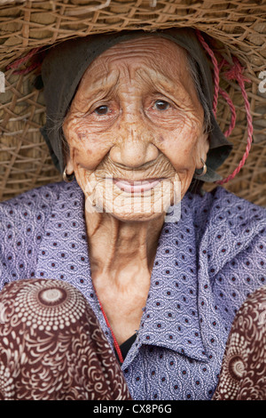 Eine schöne 93 Jahre alte Chinesin Ernte Reis die traditionelle Art und Weise mit ihren Händen den Toren Guilin, China Stockfoto