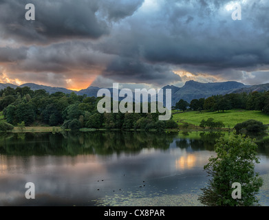 Sonnenuntergang über Langdale Pikes mit Loughrigg Tarn im Vordergrund Stockfoto