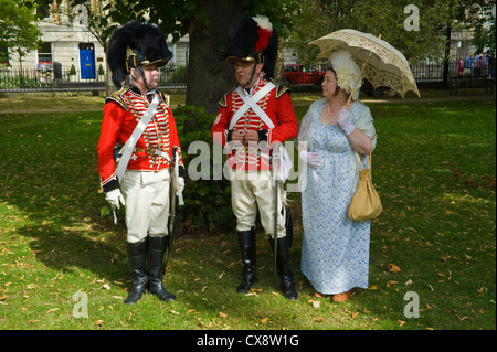 Red Coat Soldaten in uniform Regency posieren mit Dame in Tracht im Park im Stadtzentrum von Bad zu Beginn der Jane Austen Festival Stockfoto