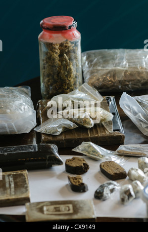 Blöcke/Ziegel von Cannabisharz mit Gläsern und Taschen von Cannabiskraut auf dem display Stockfoto