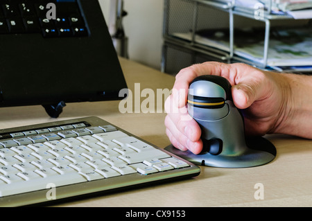 Man verwendet eine Pinguin vertikale ergonomische Computermaus für Menschen mit Schmerzen am Handgelenk Stockfoto