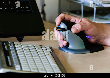 Man verwendet eine Pinguin vertikale ergonomische Computermaus für Menschen mit Schmerzen am Handgelenk Stockfoto