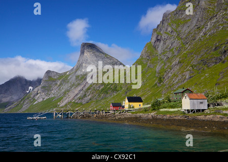 Kleinen norwegischen Dorf Fjord in der Nähe von Reine auf den Lofoten-Inseln, mit dramatischen Berggipfel überragt Stockfoto