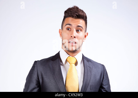 Junger Geschäftsmann mit einem Angst-Ausdruck auf seinem Gesicht (isoliert auf grau) Stockfoto
