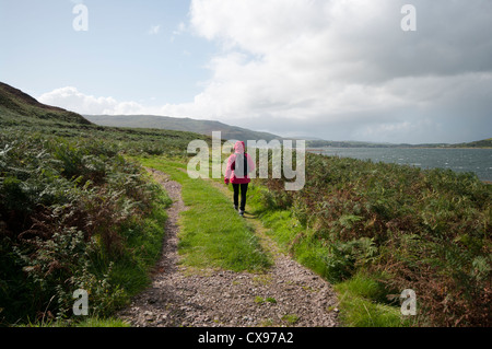 Rückansicht einer Frau Person zu Fuß durch die Landschaft tragen wasserdichte Kleidung und Rucksack Stockfoto