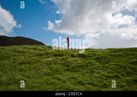 Vorderansicht einer Frau Person zu Fuß durch die Landschaft tragen wasserdichte Kleidung und Rucksack Stockfoto