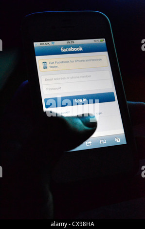 ein Mann hält ein Iphone mit der Facebook-app Stockfoto