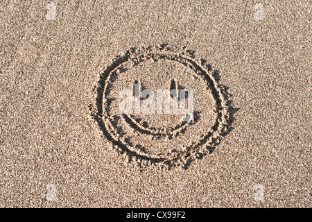 Smiley-Gesicht auf Strandsand gezeichnet Stockfoto