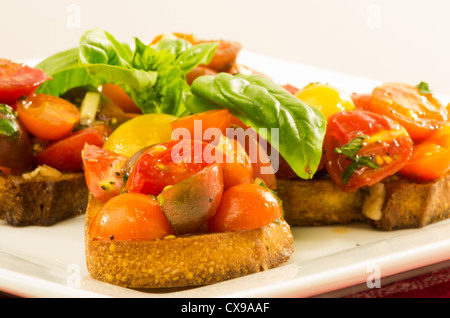 Frische Bruschetta mit gemischten Tomaten Käse und Basilikum auf weißen Teller Stockfoto