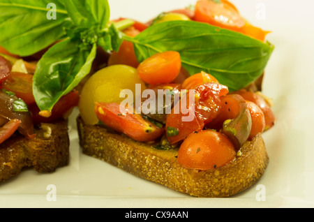 Frische Bruschetta mit gemischten Tomaten Käse und Basilikum auf weißen Teller Stockfoto