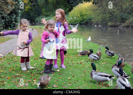 Drei junge Mädchen, die Fütterung Brot zu Enten am Ufer eines Flusses in Hubbards Hügeln im Herbst. Stockfoto