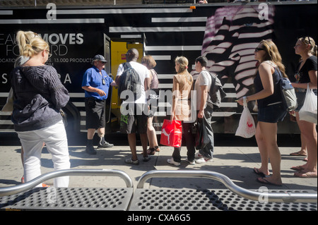 Touristen Schlange stehen, um eine Sightseeing Tourbus Werbung Sephora im Stadtteil Soho von New York geben Stockfoto